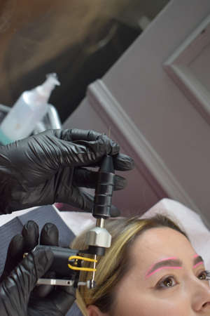 Cosmetologist who applies permanent eyebrow make-up to a young girlの写真素材