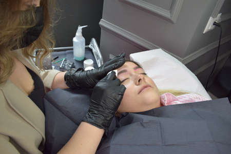 Cosmetologist who applies permanent eyebrow make-up to a young girlの写真素材