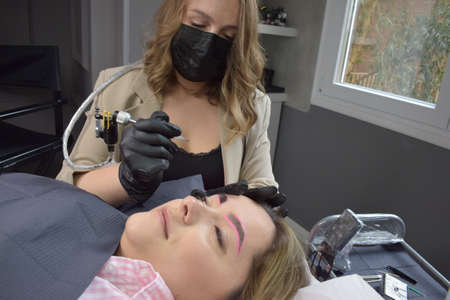 Cosmetologist who applies permanent eyebrow make-up to a young girlの写真素材