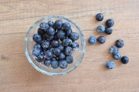 A glass bowl with frozen blueberries in wood backgroundの写真素材