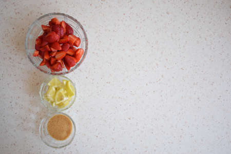 A bowl of strawberries, a lemon and brown sugar.の写真素材