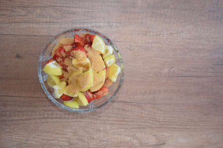 A bowl of strawberries, a lemon and brown sugar.の写真素材