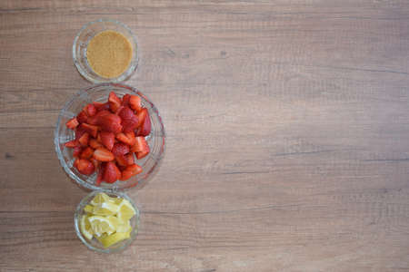 A bowl of strawberries, a lemon and brown sugar.の写真素材