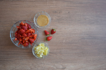 A bowl of strawberries, a lemon and brown sugar.の写真素材