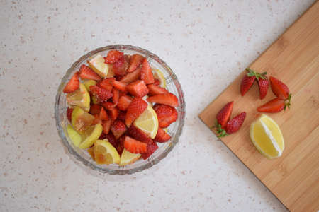 A bowl of strawberries, a lemon and brown sugar.の写真素材