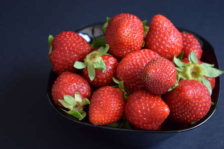 A ration of fresh strawberries on a black backgroundの写真素材