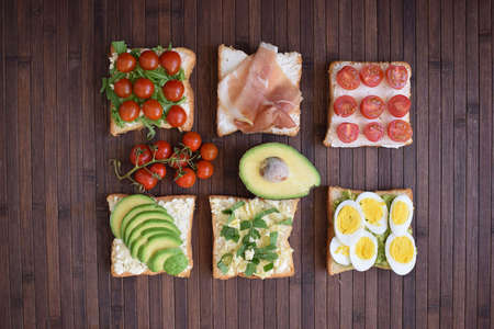Healthy toast for breakfast with avocado, eggs, tomatoes, arugula etcの写真素材