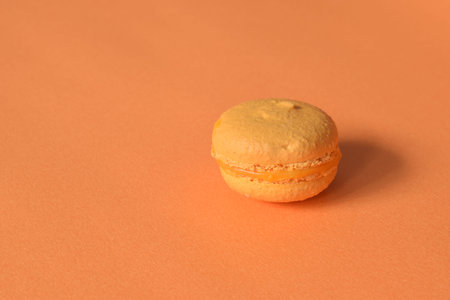 An orange macaron on a minimalistic orange background.の写真素材