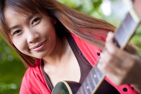 Young woman playing guitar at outdoor, shallow depth of fieldの写真素材