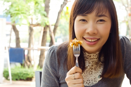 Woman eating waffle in side walk cafeの写真素材