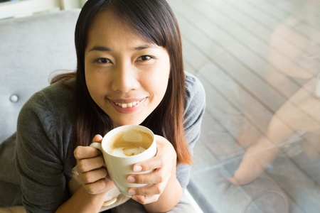 Young woman drinking  hot coffee in sidewalk cafeの写真素材