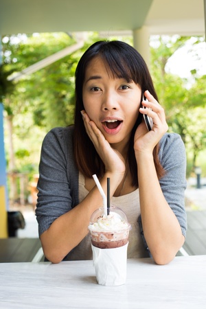 Young girl using mobile phone look surprising and exciting in the cafe restaurantの写真素材