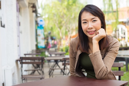 Young asian woman sitting at sidewalk cafeの写真素材