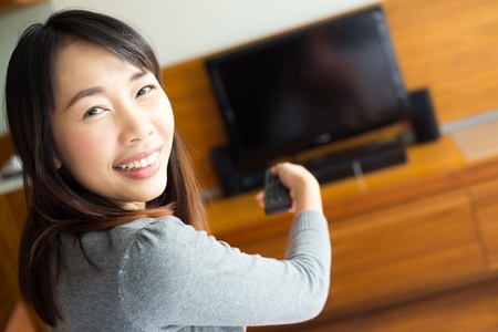 Woman with remote control switching channelsの写真素材