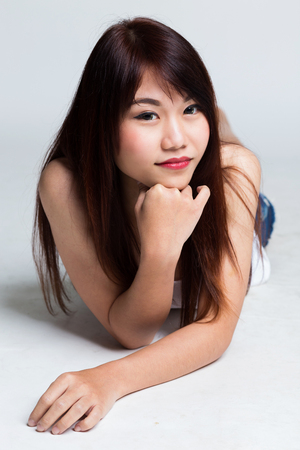 Young sexy asian woman in white shirt lying down on the floorの写真素材