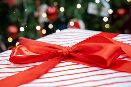 Christmas gift white box red ribbon bow with garland lights bokeh illumination unfocused background winter holidays happy time seasonの写真素材