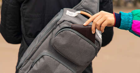 pocket theft money wallet from bag by female tender hand outdoor street criminal action concept photographyの写真素材