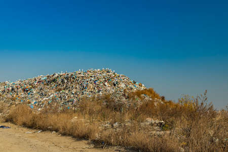 environmental pollution concept nowadays actual concept of trash mountain in outskirts dump with blue sky background empty copy space for your textの写真素材