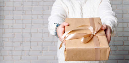 holiday advertising pattern concept male hands give gift to camera on studio white interior brick wall background empty copy space for your text hereの写真素材