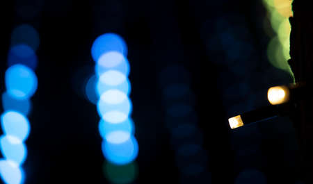 garland lamp yellow illumination blurred unfocused dark night background with blue bokeh, minimalism Christmas pattern with empty copy space for your text or inscriptionの写真素材