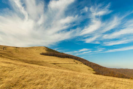 mountains hill dry grass land highland environment scenic view photography in clear weather day time and vivid blue sky fluffy white clouds background empty copy space.の写真素材