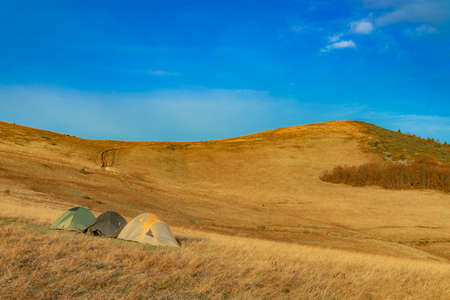 travel life style picture of three tents camp in highland environment space with mountain peak background clear weather day spring time seasonの写真素材