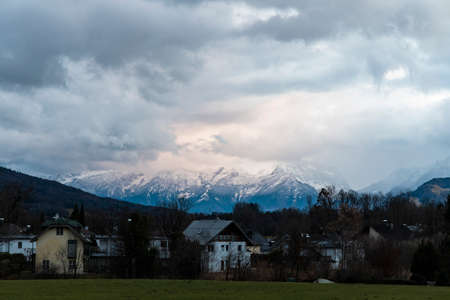 European village in Austria house in evening twilight lighting landmark view with picturesque landscape background of winter time snowy mountain peak and cloudy gray skyの写真素材