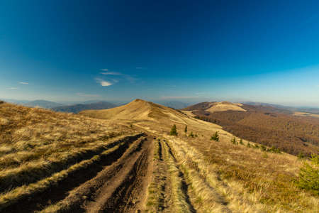 dirt trail along mountain range highland scenic landscape photography in autumn time season clear weather day without people, blue sky background empty copy spaceの写真素材