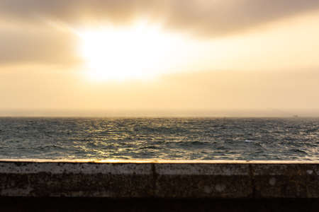 Mediterranean sea waterfront scenic view wavy surface to horizon with cloudy sky and sun set light and rays background, copy space for your textの写真素材