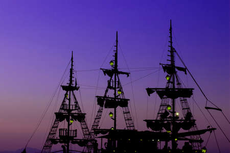 romantic vacation cruise ship wooden medieval mast dark silhouette and gas lamps illumination on blue and purple sunset evening sky background copy space for textの写真素材