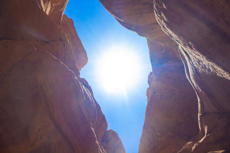 beautiful colorful desert canyon scenery view from below in narrow space between rocks with bright blue sky backgroundの写真素材