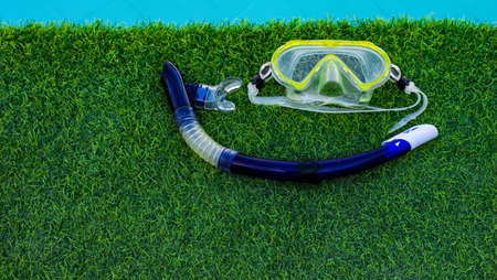 snorkeling mask and tube life style water activity hobby poster wallpaper picture with green grass and swimming pool background and empty copy space for your text.の写真素材