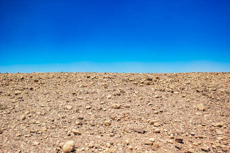 minimalism landscape of desert wasteland dry stone ground nature background horizontal board with empty blue skyの写真素材
