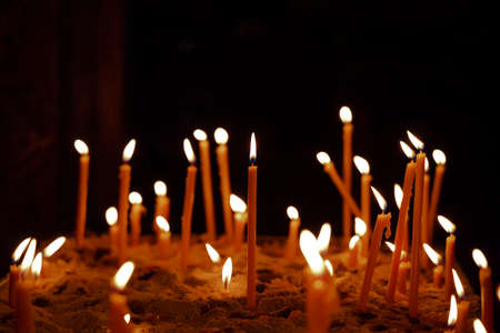 yellow illumination of candle pedestal church religion atmosphere black background empty copy space for your textの写真素材