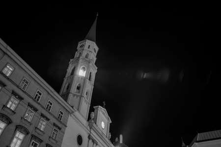 vintage style black and white monochrome long exposure photography of old European city center of Vienna capital of Austria cathedral tower illumination from window and rays of lightの写真素材