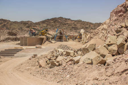 digging mine not working industry factory cranes and machines iron and steel objects in sand stone rocky desert hills dryの写真素材