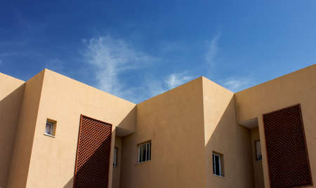 corners and lines geometric shapes of concrete small building apartment foreshortening from below with blue skyの写真素材