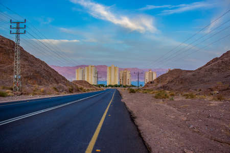 entrance road to Israeli city Eilat on Gulf of Aqaba Red sea bay scenic place, photography with living buildings background in colorful evening time and desert suburb Middle Eastの写真素材
