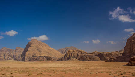 desert landscape picturesque mountain pyramid shape sand stone range around sand valley in Wadi Rum Jordan Middle East nature scenic  destination wallpaper backgroundの写真素材
