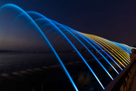 highlighted by blue and yellow colors fountain streams waterfront alley way park district at night long exposure pictureの写真素材