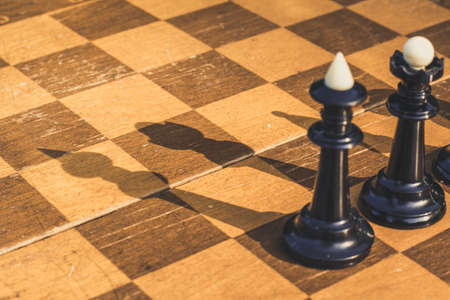 creative concept shot from above of chess classic desk wooden surface and black figures with shadows...