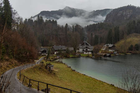 Central Europe village landmark rural scenic view in Austria moody rainy season weather time small cozy houses with road on a hill near lake surrounded my misty mountains spaceの写真素材