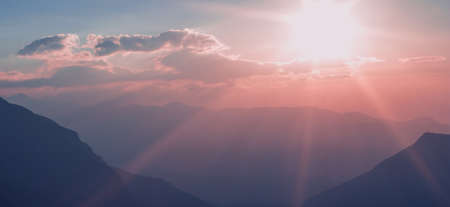 unfocused idyllic sun set rays of light above mountain silhouettes picturesque landscape wallpaper background pattern space for copy or your text here purple and phantom blue colors in Olympus Greeceの写真素材
