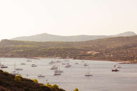 Tropic Caribbean sea bay nature landscape with place to stay of many expensive yachts boats and ship in soft orange color sunset evening romantic and atmospheric weatherの写真素材