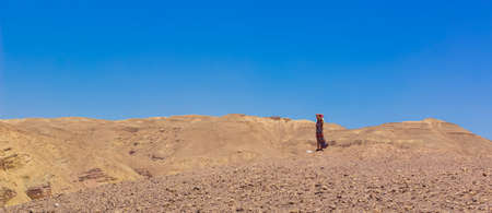 lonely woman fluttering dress portrait in dry ground global warming hot desert landscape nature environment vivid blue sky background space for copy or text here, advertising concept patternの写真素材