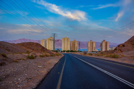 the most south Israeli city Eilat outskirts country side space urban view asphalt car road to building surrounded by sand stone desert hills landの写真素材