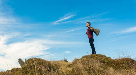 travel successful person concept poster of hiking middle adult man stay in freedom pose on top of mountain in windy weather time blue sky wallpaper background space for copy or your text hereの写真素材