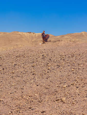 lonely female person portrait in fluttering dress on a wind in desert landscape global warming...