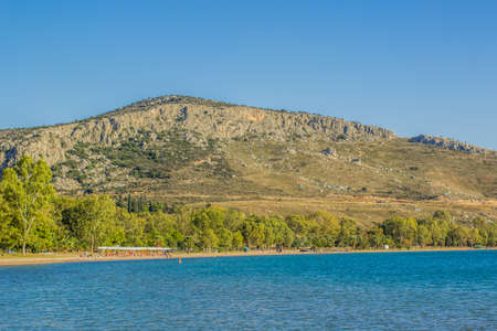 summer sea vacation and people on sand beach in bay surrounded by mountain on blue sky background copy spaceの写真素材