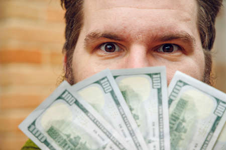 middle adult portrait half face behind money cash dollars he holdの写真素材